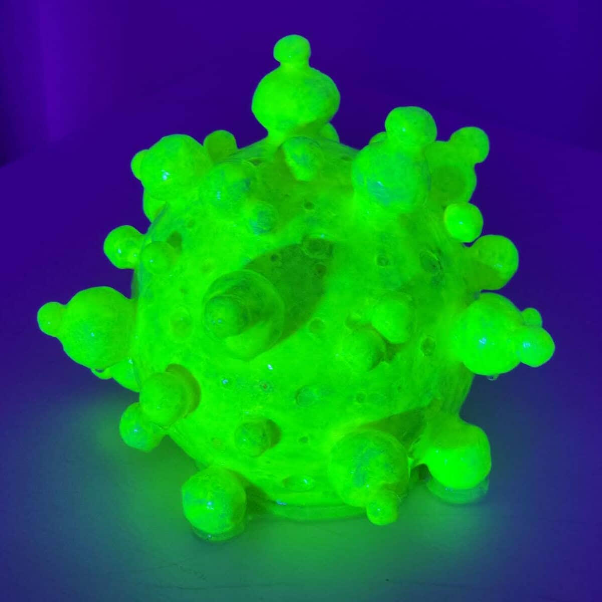 Original neon green fluorescent abstract sculpture titled "Candor Source" by Melbourne artist Michal Plis. The glowing, spherical artwork, photographed under UV light, features organic circular forms and marks the 2024 debut of the Roundism art movement.